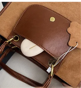 Detail of a brown tote bag featuring textured leather mix and a front pocket for accessories