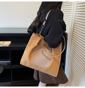Detail of large brown suede tote bag with leather pocket and metal chain shoulder strap