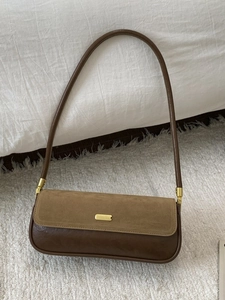 Chic brown two-tone underarm bag with suede flap and vintage leather finish on a white rug