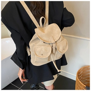 Detail view of beige matte leather backpack with front utility pockets on a model