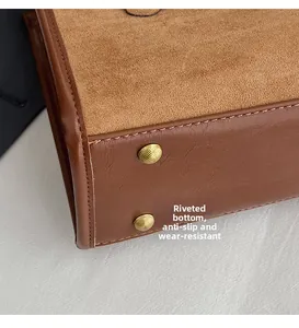 Close-up of golden metal studs on brown leather tote bag bottom for wear resistance