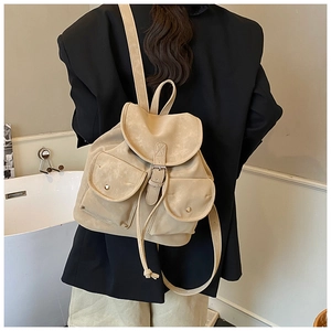 Back view of a beige vintage backpack with flap closure and pockets on model