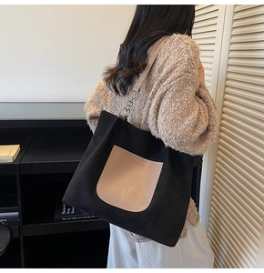 Detail of a large black tote bag with khaki pocket and chain strap worn by a model