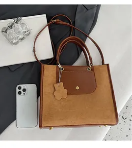 Detailed comparison of brown tote bag size with a smartphone and premium suede texture