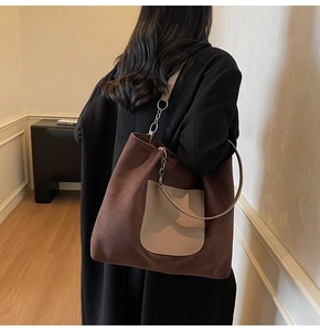 Brown suede tote bag with beige pocket and silver chain strap detail on model