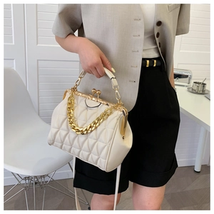 Detail of cream white quilted doctors bag featuring gold chain handle and vintage metal clasp