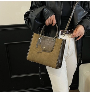 Detail of retro brown tote bag with suede texture, leather strap and cute bear charm