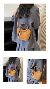 Detailed view of camel suede bucket bag with round handles and beaded tassel accessory