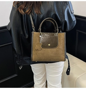 Detail of suede and leather mix tote bag with gold ring and bear charm on model