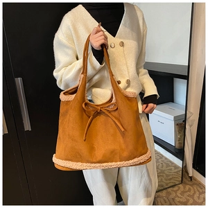 Detail of camel suede tote bag featuring plush faux fur trim and delicate bow accent
