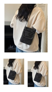 Close-up of a dark grey denim mini crossbody phone bag with silver metal snap button
