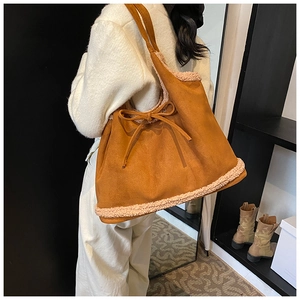 Detail of suede tote bag with plush faux fur trim and decorative side bow on the strap