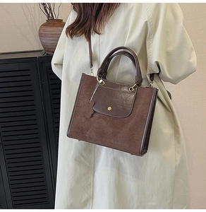 Detailed close-up of dark brown tote bag featuring mixed textures and golden clasp