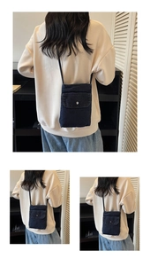 Detail view of small denim crossbody bag featuring a silver metal buckle and flip cover