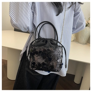 Détail d'un sac seau à paillettes noires avec fermeture à cordon et chaîne argentée