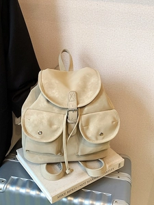 Minimalist beige travel backpack with flap belt buckle and double front pockets on suitcase