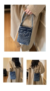 Detail of blue denim crossbody bag featuring a front flap pocket and adjustable strap