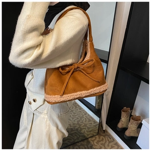 Close-up of caramel suede hobo bag with sherpa fleece trim and a decorative bow tie