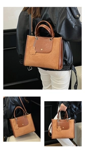 Close-up of brown suede tote bag featuring a decorative bear pendant and shoulder straps
