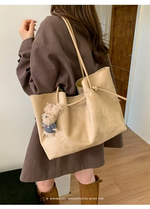 Detail of tan suede tote bag featuring adjustable knot straps and a cute dog plush charm