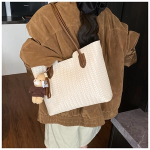 Détail du sac cabas tissé blanc cassé avec anses en cuir marron et pendentif ours