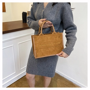 Brown suede tote bag with letter print shown in a stylish indoor lifestyle setting