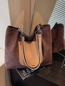 Large vintage brown suede tote bag with chain strap on a black mirrored surface