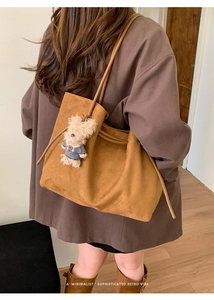 Detail of camel suede tote bag with cute bear pendant and large interior space