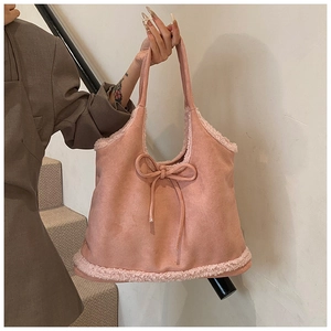 Detail of pink faux suede tote bag featuring plush lamb wool trim and bow drawstring detail