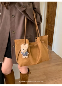 Close-up of retro brown suede tote bag with a cute teddy bear charm on the strap