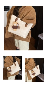 Detail of cream woven tote bag with brown leather handles and a cute bear charm accessory