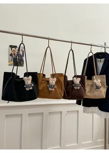 Detail view of four minimalist suede tote bags in black, yellow, brown, and beige with teddy charms