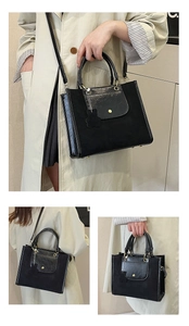 Detail of black tote bag with contrasting textures, shoulder strap and bear charm