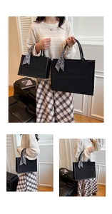 Detail of black tote bag with embossed letters and decorative silk scarf handle wrap