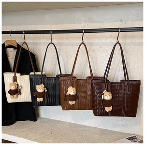 Detail showing woven texture of four large tote bags in beige, black, and brown with charms