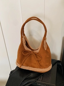 Caramel suede tote bag with faux shearling trim and decorative bow on minimalist background