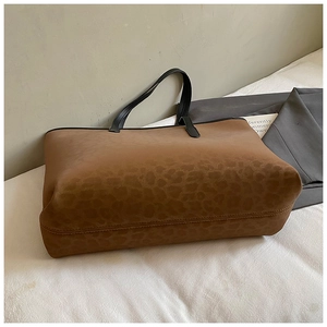 Close-up of leopard print tote bag with brown texture and black leather handles