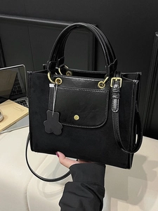 Chic black tote bag with suede paneling, gold hardware, and bear charm for 2025 fashion