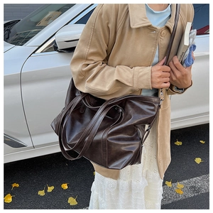 Detail of dark brown faux leather tote bag showing smooth texture and reinforced handles