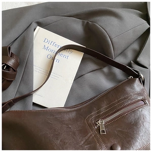 Detail of dark brown leather tote bag with functional front zipper pocket and retro white stitching