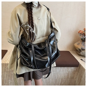 Minimalist black oversized underarm tote bag shown on model in a modern interior setting