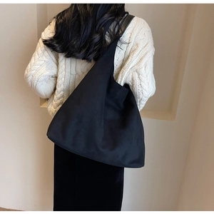 Gros plan du sac fourre-tout noir en daim montrant la texture et la coupe souple porté