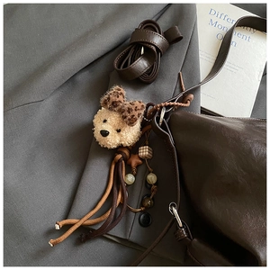Detail of plush bear charm with leopard bow on dark brown faux leather tote bag