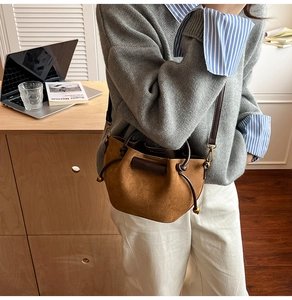 Brown suede drawstring bucket bag worn by model in a minimalist lifestyle setting
