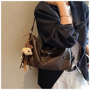 Close-up of deep brown vintage tote bag with zipper detail and plush puppy charm