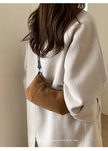 Borsa a spalla in pelle scamosciata marrone indossata da modella con cappotto beige