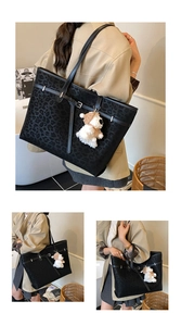 Detailed macro view of black leopard print tote bag with a cute plush bear pendant accessory