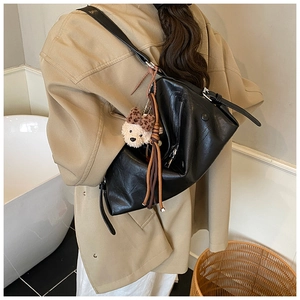 Detail of black PU leather tote bag with a cute plush bear charm and leopard bow
