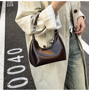 Close-up of vintage brown patent leather shoulder bag with metallic silver ball charm
