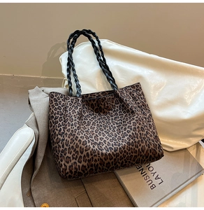 Detail of leopard print tote bag with black woven handles and spacious interior design